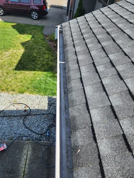 Clean gutter before guard installation, work tools visible
